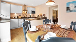 A modern kitchen with white cabinets, a central island, and a dining area with a wooden table and chairs.