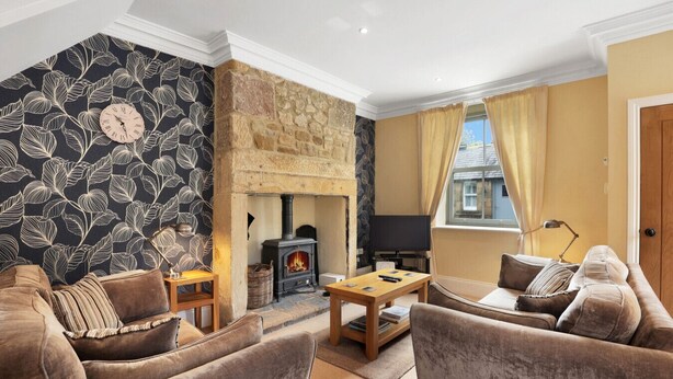A cozy living room with a stone fireplace, a television, and comfortable seating.