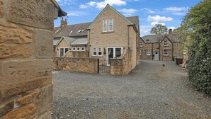 A stone building with a gravel driveway and a gated entrance.