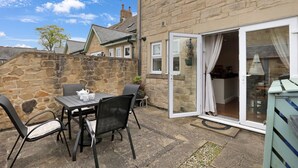 A stone wall, a table with chairs, and a sliding glass door leading to a kitchen.