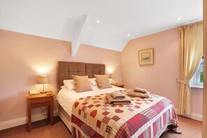 Une chambre à coucher avec un grand lit, deux tables de chevet, une fenêtre avec des rideaux et un plafond doté d’un puits de lumière.