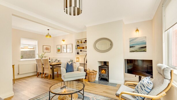A cozy living room with a fireplace, a dining area, and a TV. - Cherry Tree House- North East Escapes (Amble)