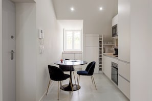 A modern kitchen with a dining area, white cabinetry, and a window providing natural light. - Lisbon Nest 2BR - Two Bedroom Apartment, Sleeps 5 (Lisbon)
