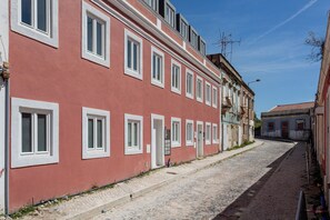 Un bâtiment rouge avec des fenêtres à cadre blanc et une rue pavée.