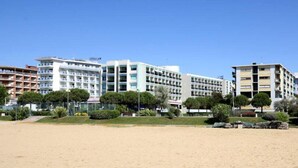 A beachfront hotel with multiple floors, balconies, and a clear view of the sea.