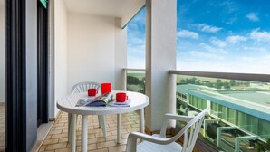 A balcony with a round table, two red cups, and a magazine.