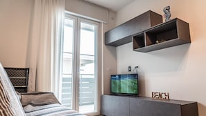 Una sala de estar moderna con un amplio ventanal corredero, un televisor de pantalla plana y un estante empotrado con objetos decorativos.