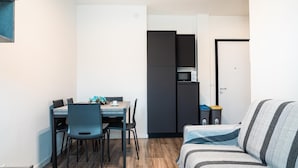 Un espacio habitable compacto con comedor, kitchenette y cama.