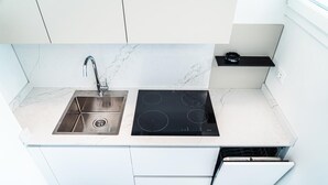 A modern kitchen with a stainless steel sink, black induction cooktop, white cabinets, and a black countertop.