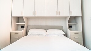 A bedroom with a large bed, two bedside tables, and a built-in wardrobe with multiple compartments.