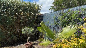 Un jardín con diversas plantas, una esfera metálica decorativa y un muro de piedra.