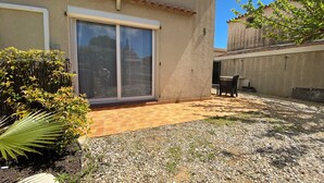 Una casa con un patio, una puerta corrediza de vidrio y una pequeña zona de estar al aire libre.
