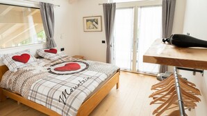 Une chambre avec un lit en bois, une fenêtre avec des rideaux, une commode en bois et un étendoir fixé au mur.