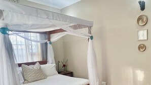 Una camera da letto con un letto a baldacchino, un comodino, una lampada e un punto luce a parete.