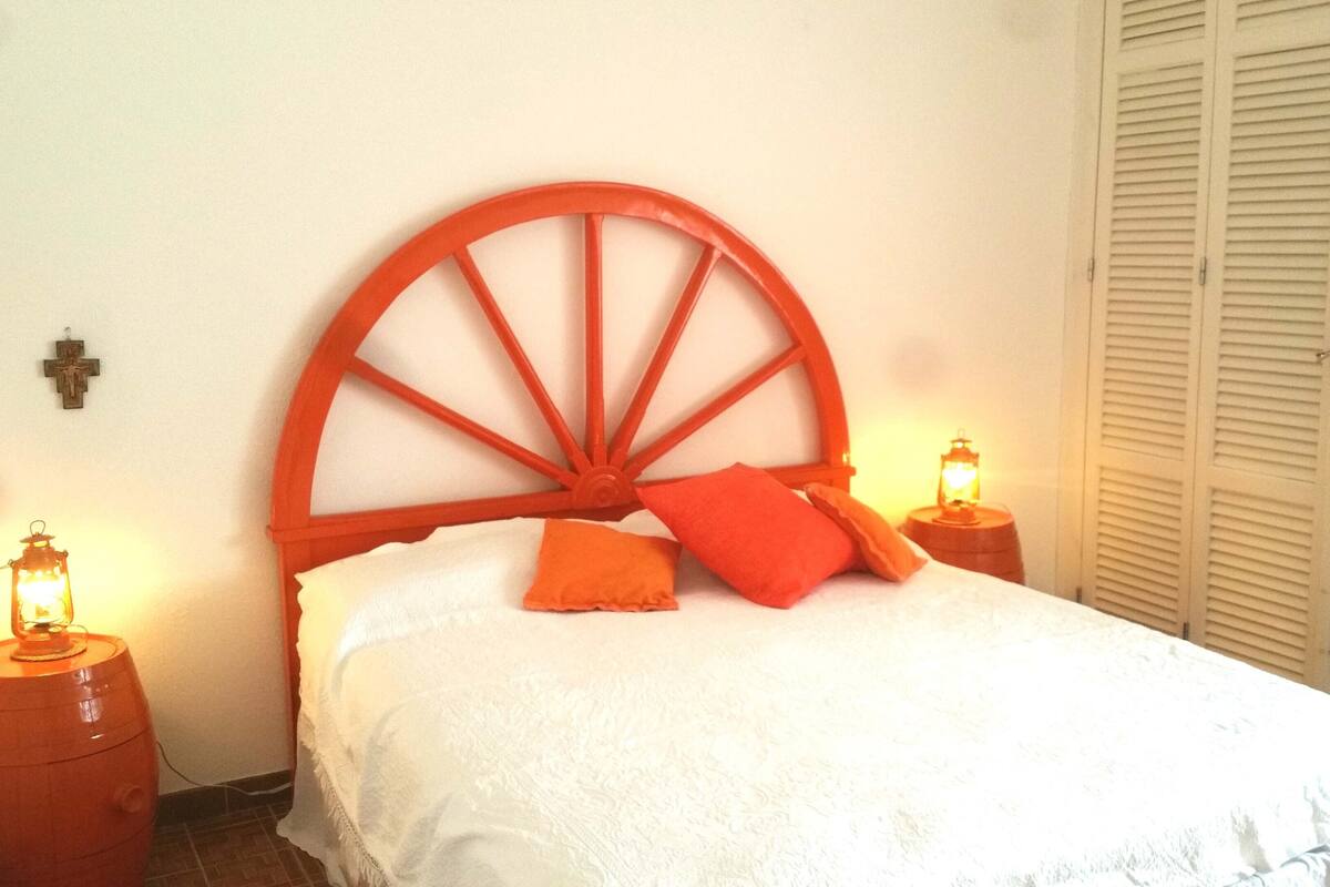 A bed with a wooden headboard, two bedside lamps, and a white bedspread.