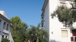 A residential street with two-story houses, parked cars, and lush greenery. - TRIVANO PARCO ULIVI SECONDO PIANO (Cirella)