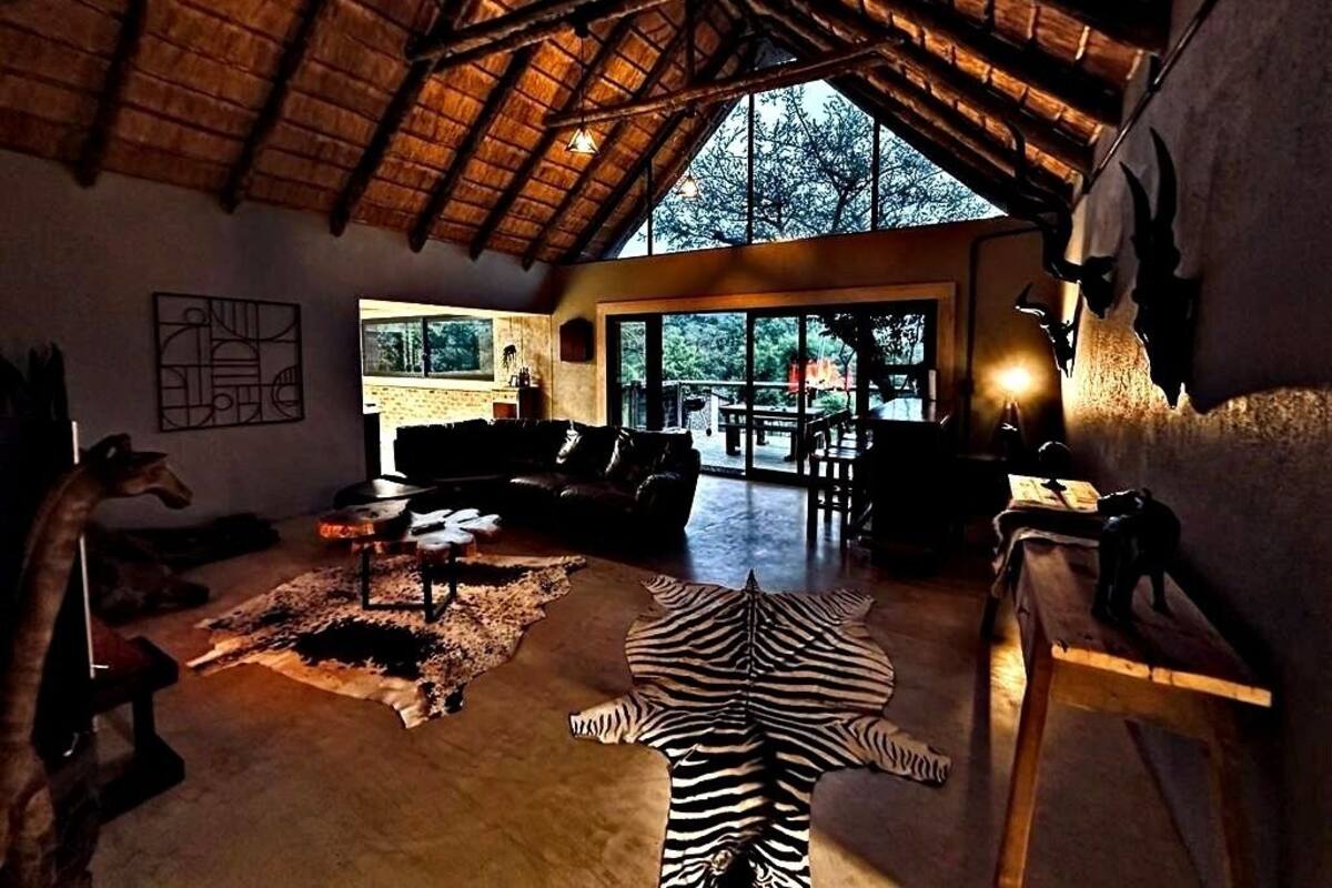 Amplia sala de estar con techo alto, un ventanal grande y un alfombra de zebra.