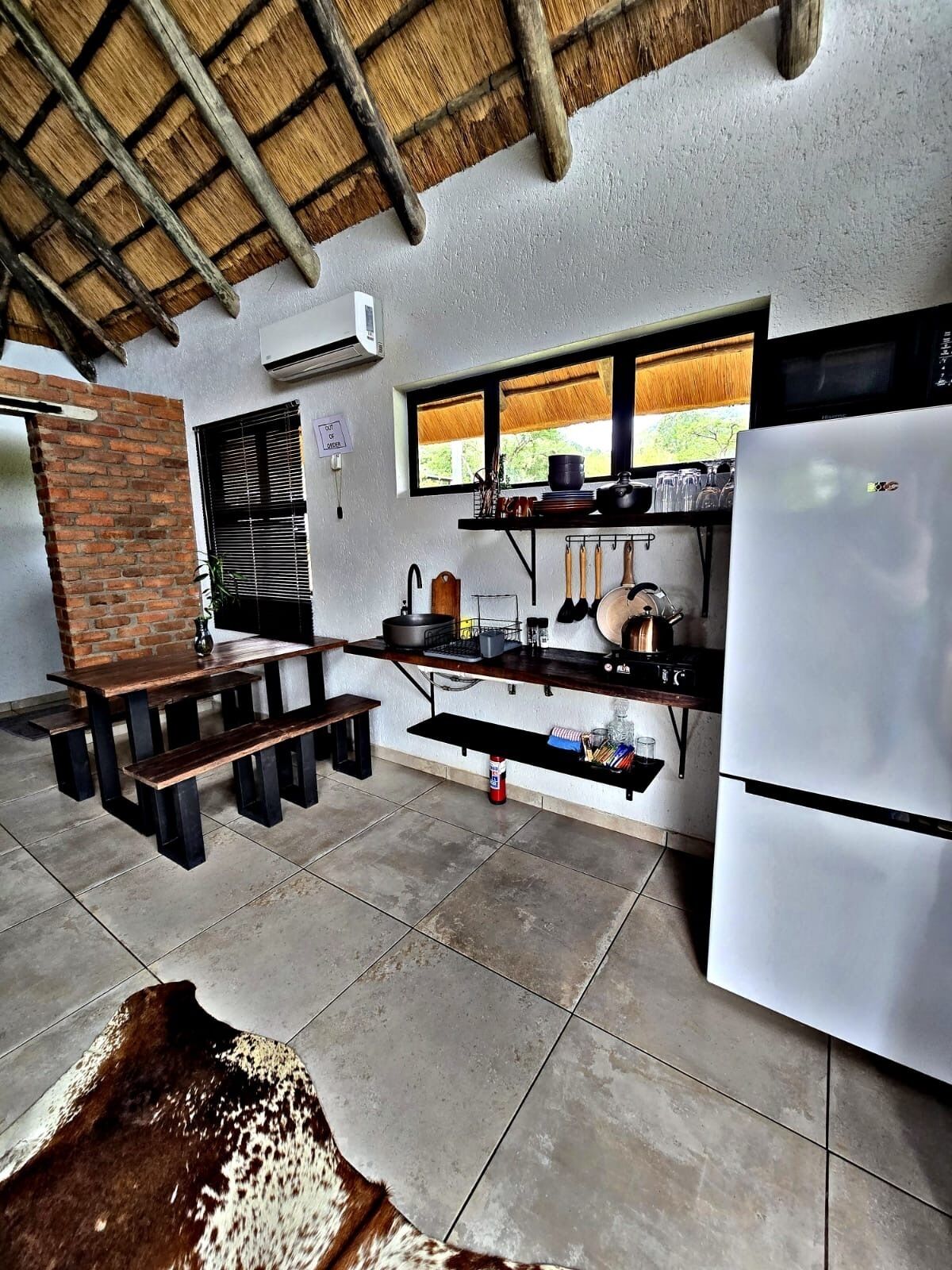 Una cocina compacta con refrigerador empotrado, una mesa de madera y ventana con vista a un jardín.