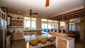Una cocina moderna con una isla central, taburetes de bar y vistas al océano.