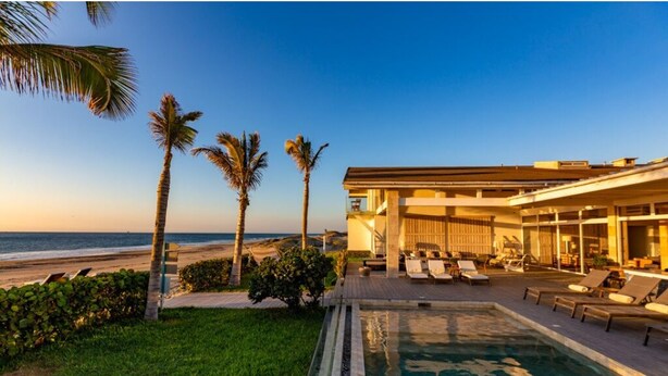 Un resort con piscina, sillas de descanso y vista al océano.