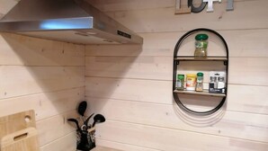 A kitchen with a stainless steel range hood, wooden cabinets, a black induction cooktop, and a spice rack with various containers. - CHALET L'AVENTURE 14km from VANNES (Sulniac)