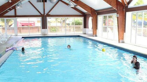 An indoor swimming pool with a wooden ceiling and large windows. - CHALET L'AVENTURE 14km from VANNES (Sulniac)