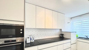 A modern kitchen with white cabinets, a Bosch oven, a coffee maker, and a toaster.