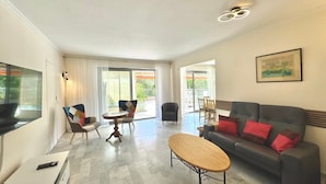 A modern living room with a sofa, a coffee table, and a dining area with chairs and a table.
