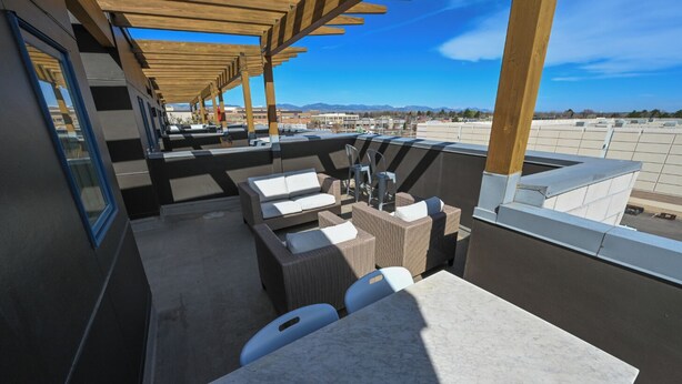 An outdoor patio with wicker furniture, a marble table, and a view of mountains.