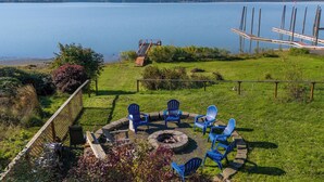 Een terras aan het meer met buitenmeubels en een vuurkorf.