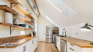 Een moderne keuken met houten planken, roestvrijstalen apparatuur en een dakraam.