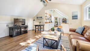 Een ruime woonkamer met een eettafel, leren bank en een keuken op de achtergrond.