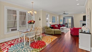 A spacious living room with a dining area, a fireplace, and a ceiling fan. - Steps to the Sand in Carolina Beach, Sleeps 10! Villa (Carolina Beach)