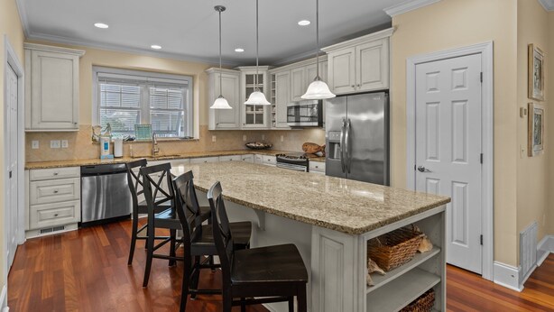 A kitchen with white cabinets, a granite countertop, stainless steel appliances, and pendant lighting. - Steps to the Sand in Carolina Beach, Sleeps 10! Villa (Carolina Beach)