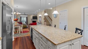 A kitchen with granite countertops, white cabinets, and a stainless steel refrigerator. - Steps to the Sand in Carolina Beach, Sleeps 10! Villa (Carolina Beach)