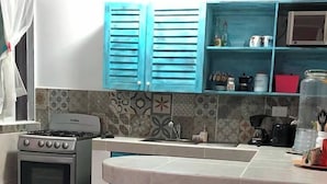 Une cuisine équipée d’une cuisinière à gaz, d’un évier et de trois tabourets.