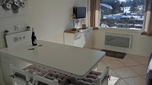 A kitchen with a dining table, chairs, a TV, and a view of a snowy landscape. - 5 minutes from the La Legette chairlift, Studio-Cabin 21m² Les Saisies (Hauteluce)