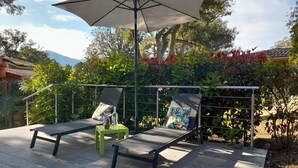An outdoor patio with two lounge chairs, a small table, and an umbrella.