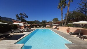 A rectangular swimming pool with a wooden deck and lounge chairs on either side.