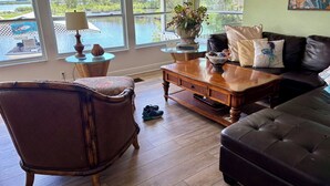 Een woonkamer met uitzicht op een meer, een houten salontafel, een leren bank en een rieten fauteuil.