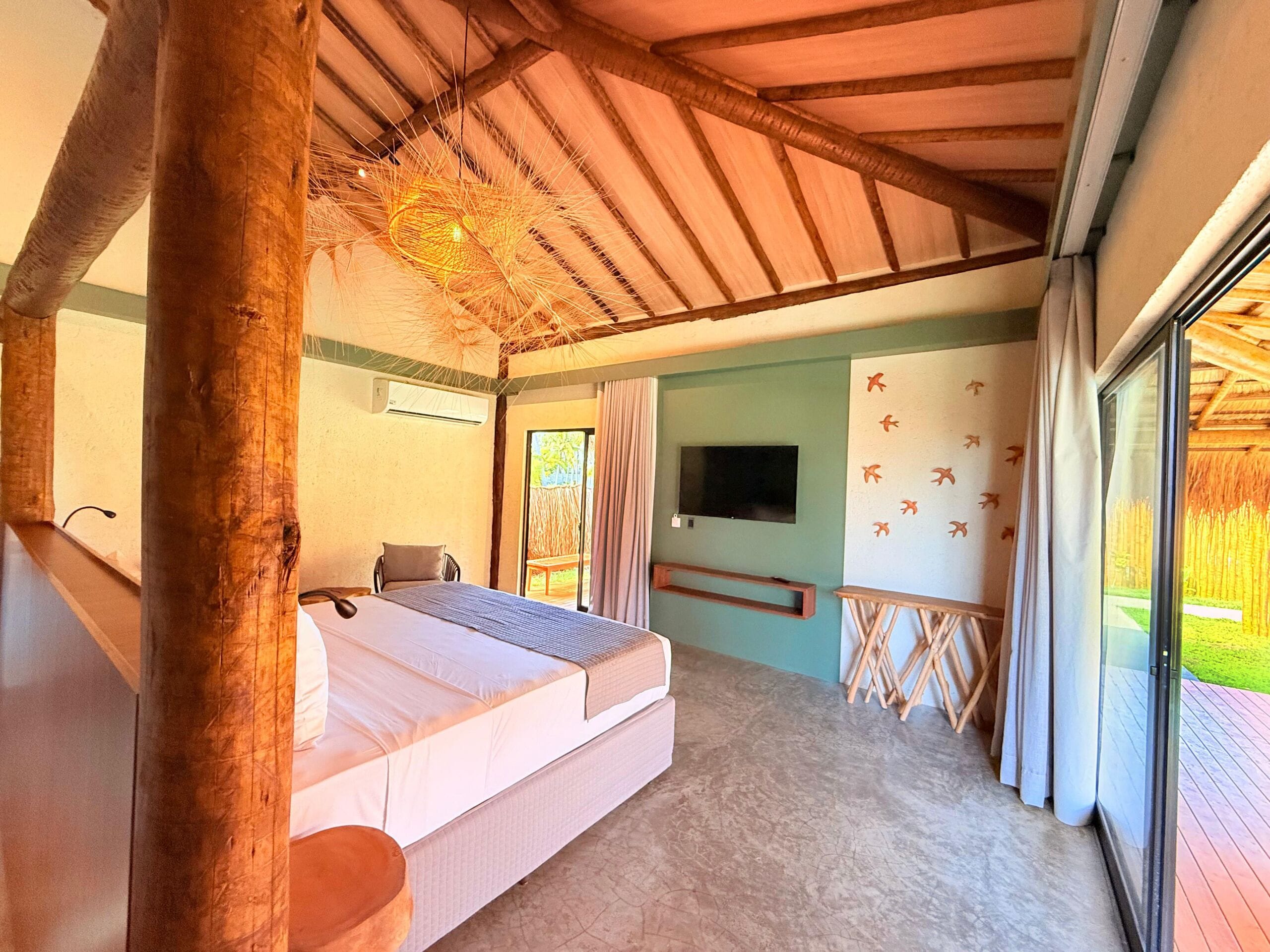 A bedroom with a bed, a TV, and a view of the outdoors.