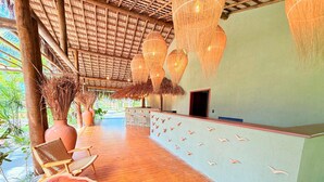 Terraza de madera con una mesa de recepción, sillas y luces colgantes.