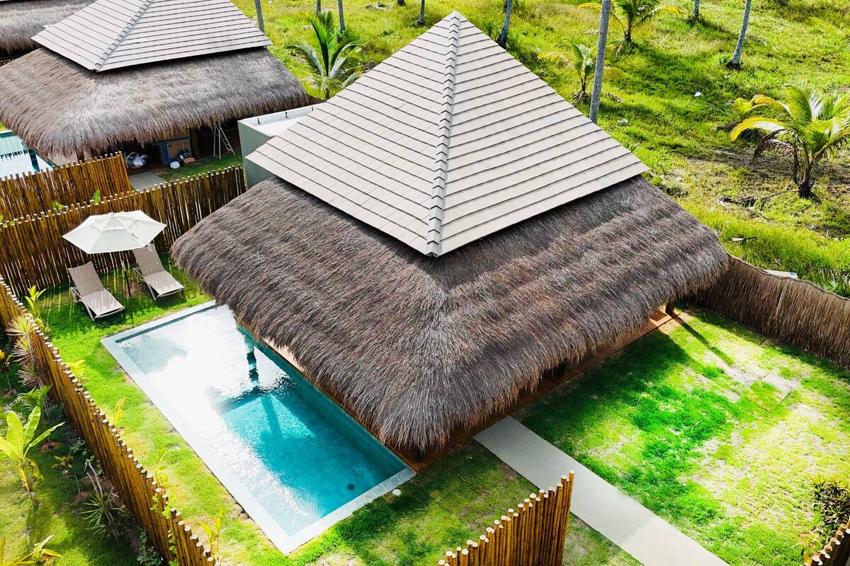 A resort with thatched-roof huts, a swimming pool, and a well-maintained garden.