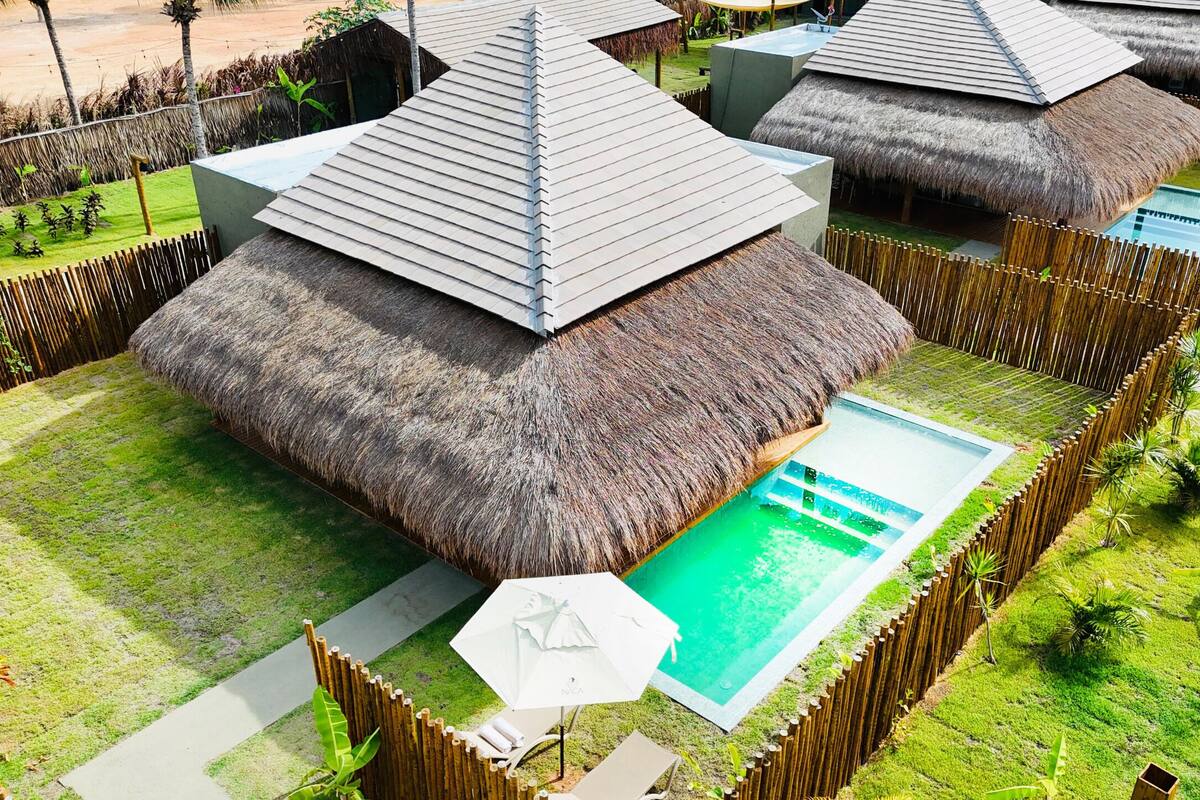 A resort with thatched-roof huts, a swimming pool, and a well-maintained garden.