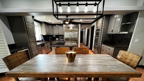 Una cocina moderna con una gran mesa de comedor de madera, armarios empotrados y una isla central.