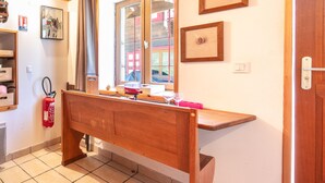 Un banco de madera en una habitación con una ventana, un extintor y cuadros en la pared.