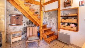 Una cocina rústica con una escalera de madera, una silla y estantes empotrados con utensilios de cocina.