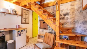 Una cocina rústica con una escalera de madera, una puerta de color amarillo brillante y una pequeña zona de estar.