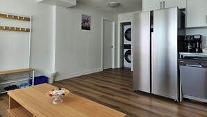 A modern kitchen with stainless steel appliances, a wooden dining table, and a laundry area. - Private south-facing suite with a full bathroom and fully equipped kitchen. (Coquitlam)