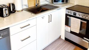 A compact kitchen with white cabinets, a built-in microwave, a toaster, and a stove. - Private south-facing suite with a full bathroom and fully equipped kitchen. (Coquitlam)